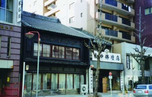 瓦屋根の古い町家と仏壇店が並ぶ通りの写真